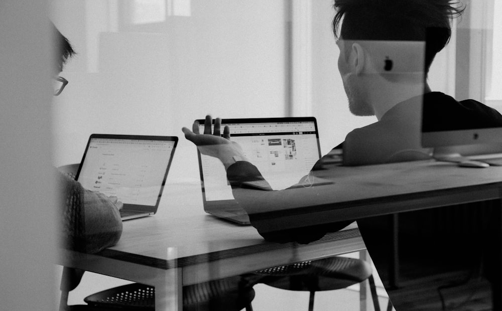 Two analysts comparing company records on laptops in an office